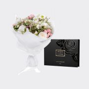 A beautiful bouquet of mixed fresh flowers, with a small box of chocolate.