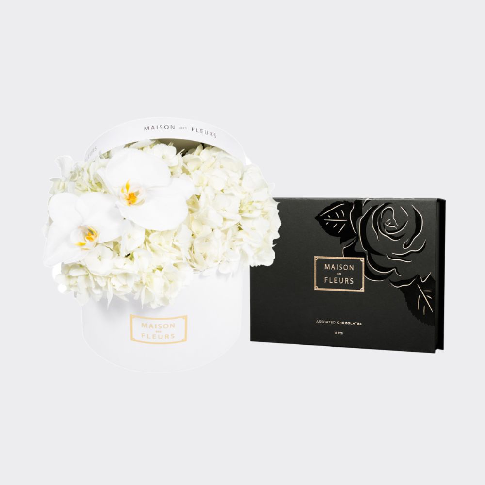 Lovely gift set of fresh white Hydrangeas with 2 orchid blooms in a white 20 cm round box, coupled with a box of 12 pieces of chocolate