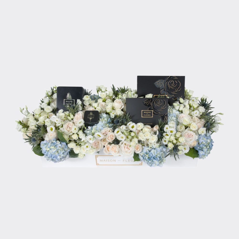 An arrangement of mixed blue Hydrangeas sprinkled with white fresh flowers accompanied by a box of premium Medjool dates and a box of chocolates.