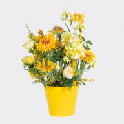 Faux sunflowers, mimosa and daisies in a yellow medium terracotta pot